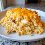 A hearty serving of cheesy chicken and rice casserole topped with melted cheddar cheese.