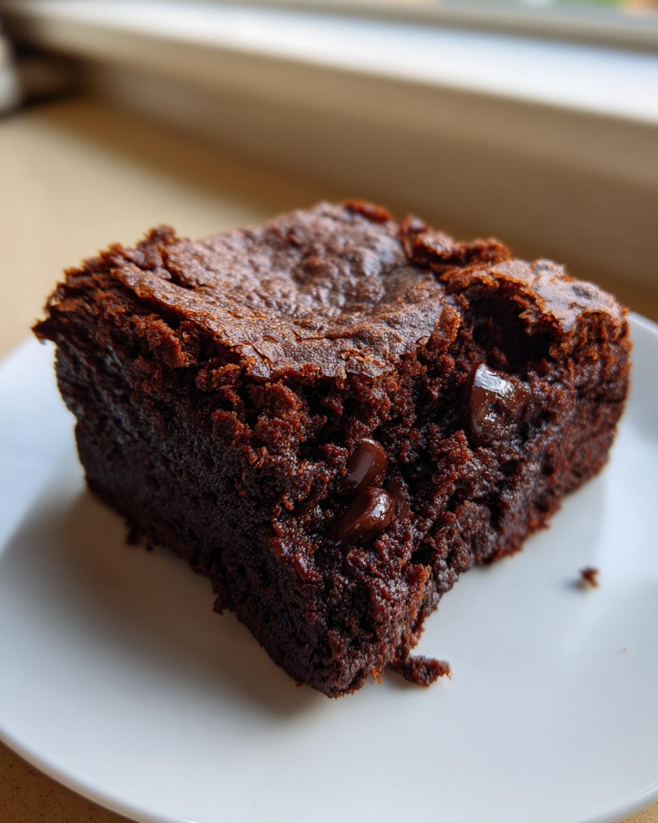 Close-up of a rich, dark chocolate square of sweet potato brownies with visible melted chocolate chips.