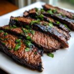 Close-up of perfectly grilled and sliced steak, glistening with marinade, topped with fresh cilantro.