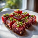Close-up of fresh, ruby-red Tuna Tartare Recipe cubes coated in sesame seeds and topped with green onions.