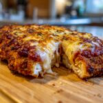 Close-up of a perfectly baked chicken parmesan recipe with crispy breading, marinara sauce, and gooey, melted mozzarella cheese pulling apart.