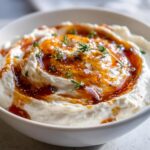 Close-up of a creamy ricotta dip swirled with honey or balsamic glaze and garnished with fresh thyme.