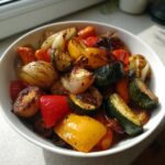 A white bowl filled with colorful, caramelized roasted vegetables including onions, zucchini, and bell peppers.