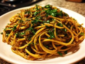 A close-up shot of a serving of caramelized onion pasta tossed with sauce and topped with fresh chopped parsley.