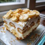 A generous slice of creamy banana pudding layered with vanilla wafers and topped with fresh banana slices.