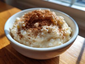 A close-up of a bowl of creamy rice pudding recipe generously dusted with ground cinnamon.