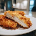 Close-up of perfectly cooked air fryer chicken tenders, showing the crispy golden breading and juicy white interior.