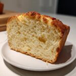 A close-up cross-section of fluffy, golden-crusted beer bread showing its airy interior texture.