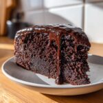 A rich, dark slice of fudgy flourless chocolate cake topped with dripping chocolate ganache.