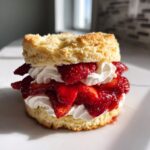 Close-up of a delicious shortcake layered with macerated strawberries and fresh whipped cream.