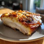 Close-up of a thick slice of baked chicken breast with a golden, crispy, herb-topped crust.