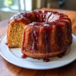 A moist bacardi rum cake, shaped like a bundt cake, covered in a dark, dripping glaze, with one slice removed.