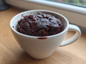 Close-up of a rich, dark chocolate chip mug cake baked inside a white ceramic mug.