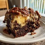 A moist slice of german chocolate poke cake topped with gooey caramel frosting and whole pecans.