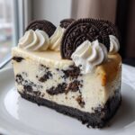 A perfect slice of rich Oreo cheesecake featuring chunks of chocolate cookies mixed in, topped with whipped cream swirls and whole Oreo cookies.