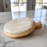 Close-up of a sugar cookie topped with thick, smooth white cookie icing recipe.