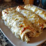Close-up of three delicious white chicken enchiladas covered in melted, slightly browned cheese sauce.