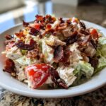 Close-up of a creamy blt chicken salad featuring chunks of chicken, lettuce, tomatoes, and generous amounts of crispy bacon.