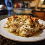 A serving of moist crock pot chicken and stuffing with a golden, herbed topping on a white plate.