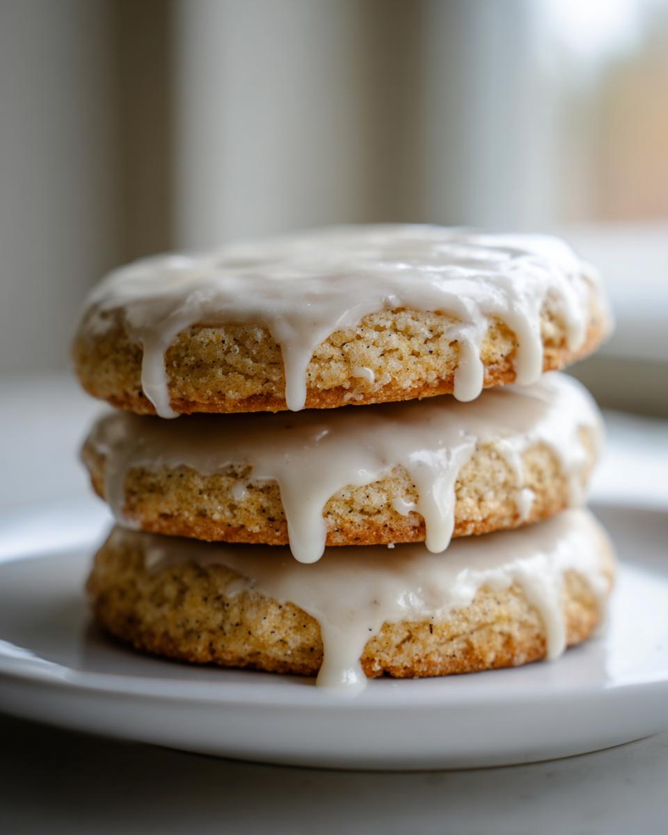 A stack of three soft earl grey cookies topped with thick, dripping vanilla glaze on a white plate.