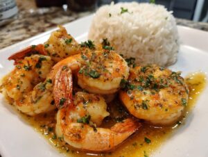 Close-up of juicy Hawaiian garlic shrimp coated in garlic butter sauce, served next to a mound of white rice.