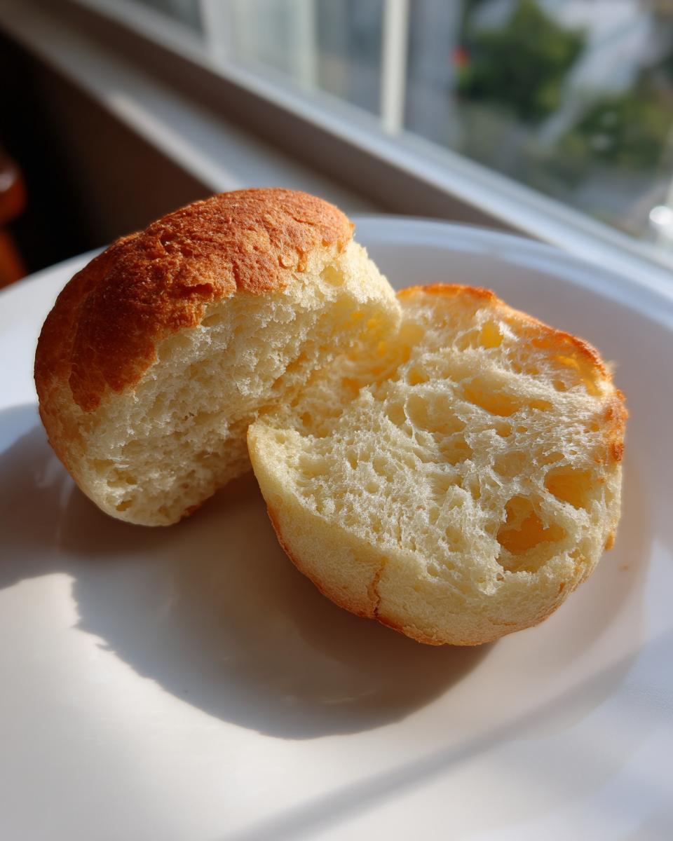 Close-up of a homemade english muffin split in half, showing the fluffy, open crumb texture.