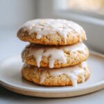Three stacked, soft earl grey cookies topped with dripping white glaze and yellow lemon zest.
