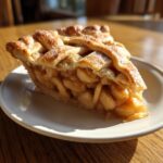 A close-up of a perfect slice of apple pie with a lattice crust, showing juicy filling, perfect for an amazing apple pie recipe.