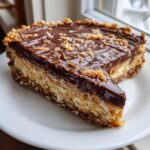 A rich slice of no-bake German chocolate pie showing layers of coconut filling and a glossy chocolate topping with pecans.