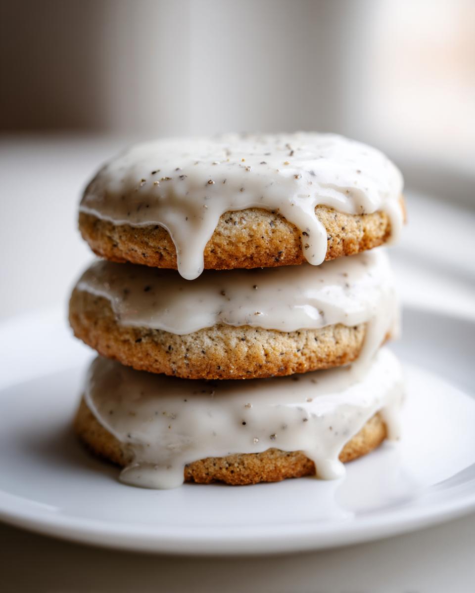 Three stacked, round earl grey cookies generously topped with a dripping white glaze speckled with tea grounds.