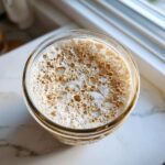 Overhead view of active sourdough starter showing many bubbles and foam in a glass jar.