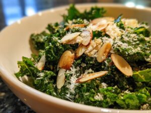 Close-up of a vibrant kale salad topped with slivered almonds and grated Parmesan cheese.