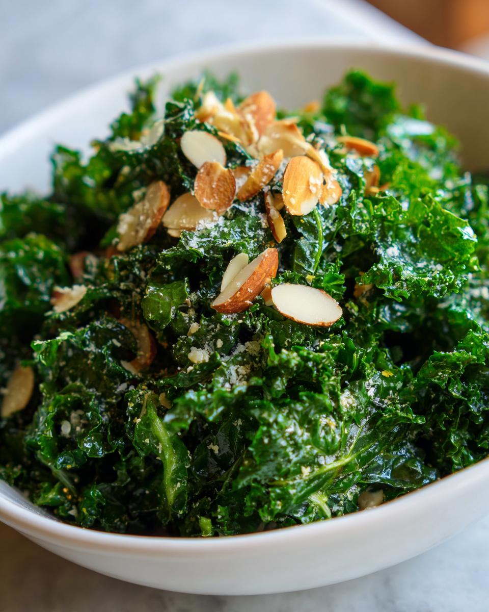 A close-up of a vibrant green kale salad topped with slivered almonds and grated cheese.