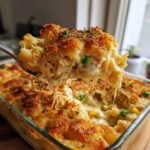 A spoonful of cheesy tuna pasta bake, showing melted cheese strings and a crispy breadcrumb topping.