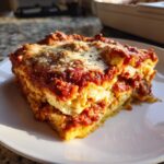A thick, layered slice of crockpot ravioli lasagna covered in rich red sauce and melted cheese.