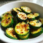 Close-up of perfectly sauteed zucchini rounds coated in a glistening garlic and spice mixture.