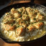 Golden pieces of chicken scampi served over creamy garlic parmesan rice in a cast iron skillet.