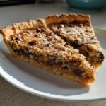 Two slices of rich Texas Trash Pie showing a thick crust, gooey filling, chocolate chips, and coconut topping.