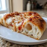 Close-up of one perfect slice of amazing cheese pizza showing melted mozzarella and a thick, airy crust cross-section.