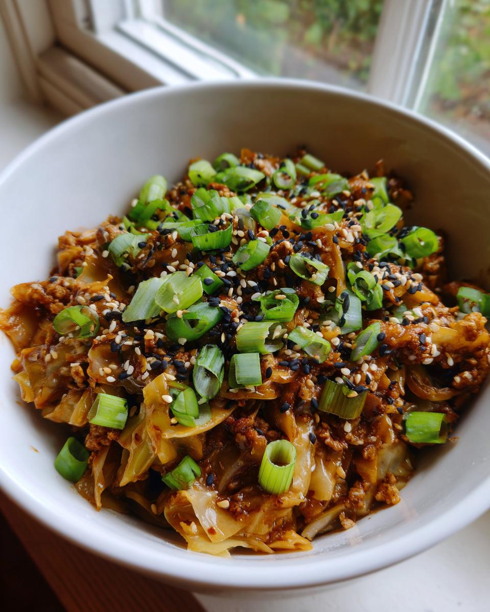 A close-up of a white bowl filled with chicken egg roll in a bowl, topped generously with sliced green onions and sesame seeds.