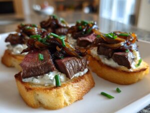 Four pieces of steak crostini featuring medium-rare steak, creamy cheese, and caramelized onions, garnished with chives.
