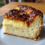 Close-up of a thick slice of bee sting cake showing the fluffy cake base, creamy vanilla filling, and sticky caramelized almond topping.