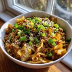 A close-up of a white bowl filled with savory chicken egg roll in a bowl, topped with scallions and sesame seeds.