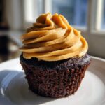 A single, decadent chocolate peanut butter cupcakes featuring dark chocolate cake and a tall swirl of peanut butter frosting.