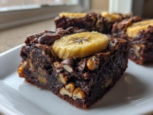 A close-up of a fudgy, rich chunky monkey brownies square topped with a banana slice and chocolate chips.