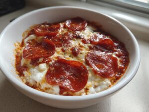 Close-up of a baked cottage cheese pizza bowl topped with melted cheese and pepperoni slices.