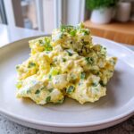 A generous scoop of creamy egg salad mixed with chopped celery and herbs, garnished with fresh dill.