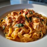 Close-up of creamy marry me chicken pasta featuring fettuccine, chunks of chicken, spinach, and sun-dried tomatoes.