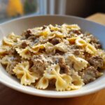 Close-up of creamy parmesan garlic beef bowtie pasta generously coated in sauce and topped with black pepper.