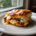 Close-up of a golden french dip stuffed biscuits overflowing with melted white cheese and savory brown filling.